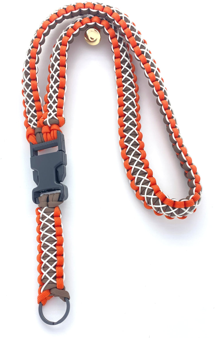 a lanyard made of orange and brown 550 paracord and white microcord and black hardware