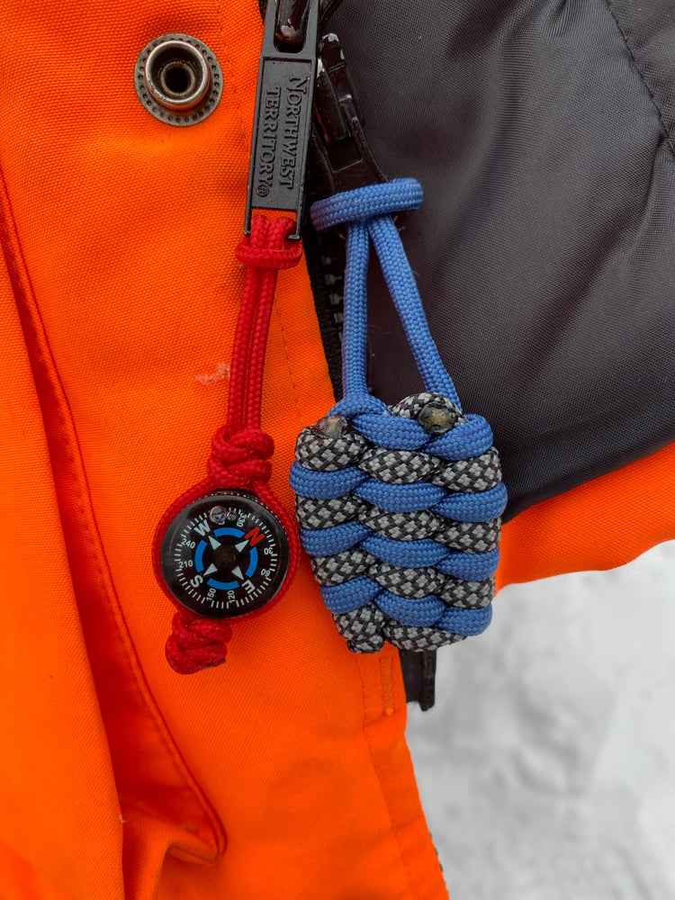 a couple of zipper pulls made with various types and colors of paracord attached to a bright orange hunting coat