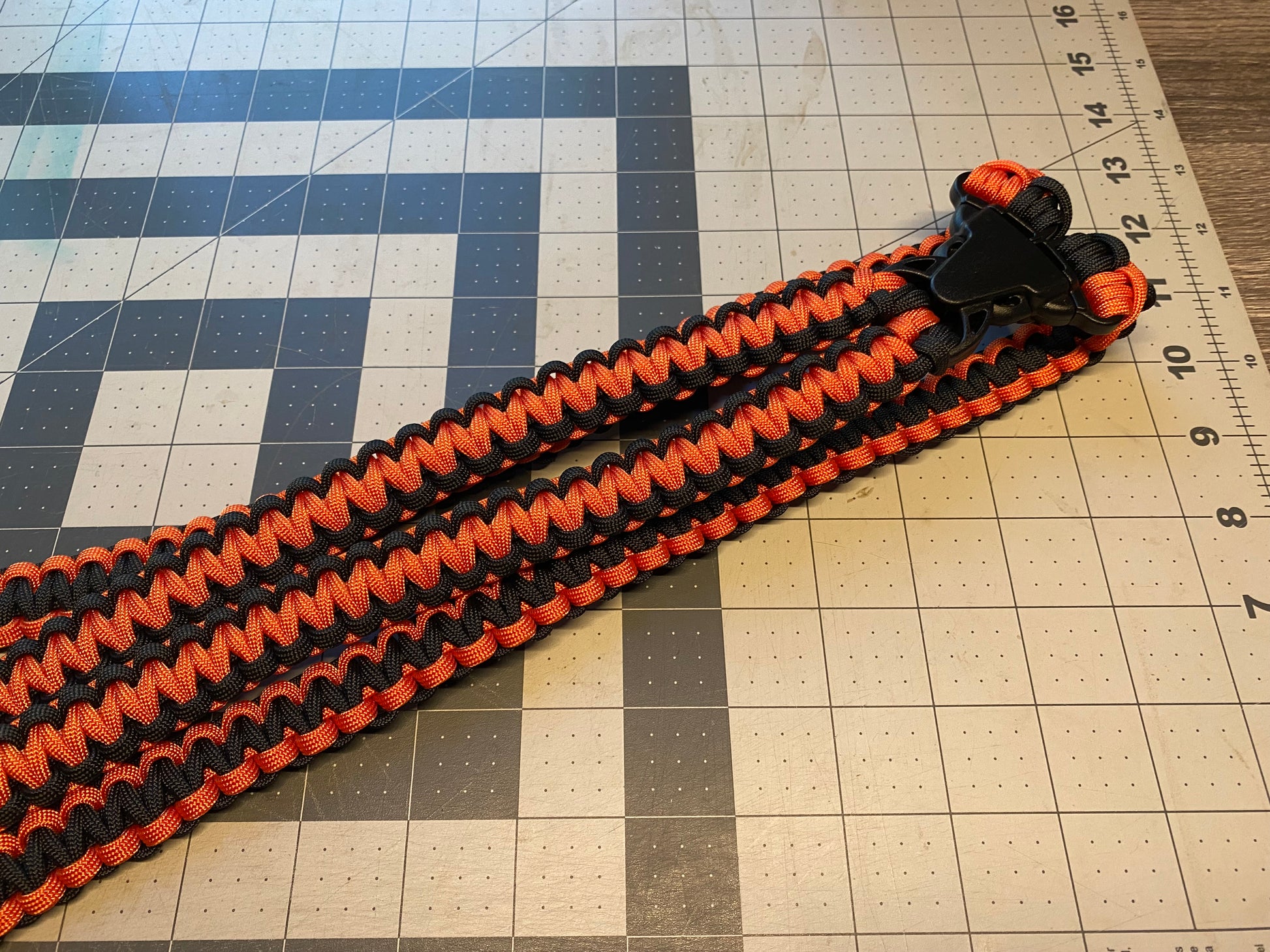a binocular harness crafted from orange and black 550 paracord