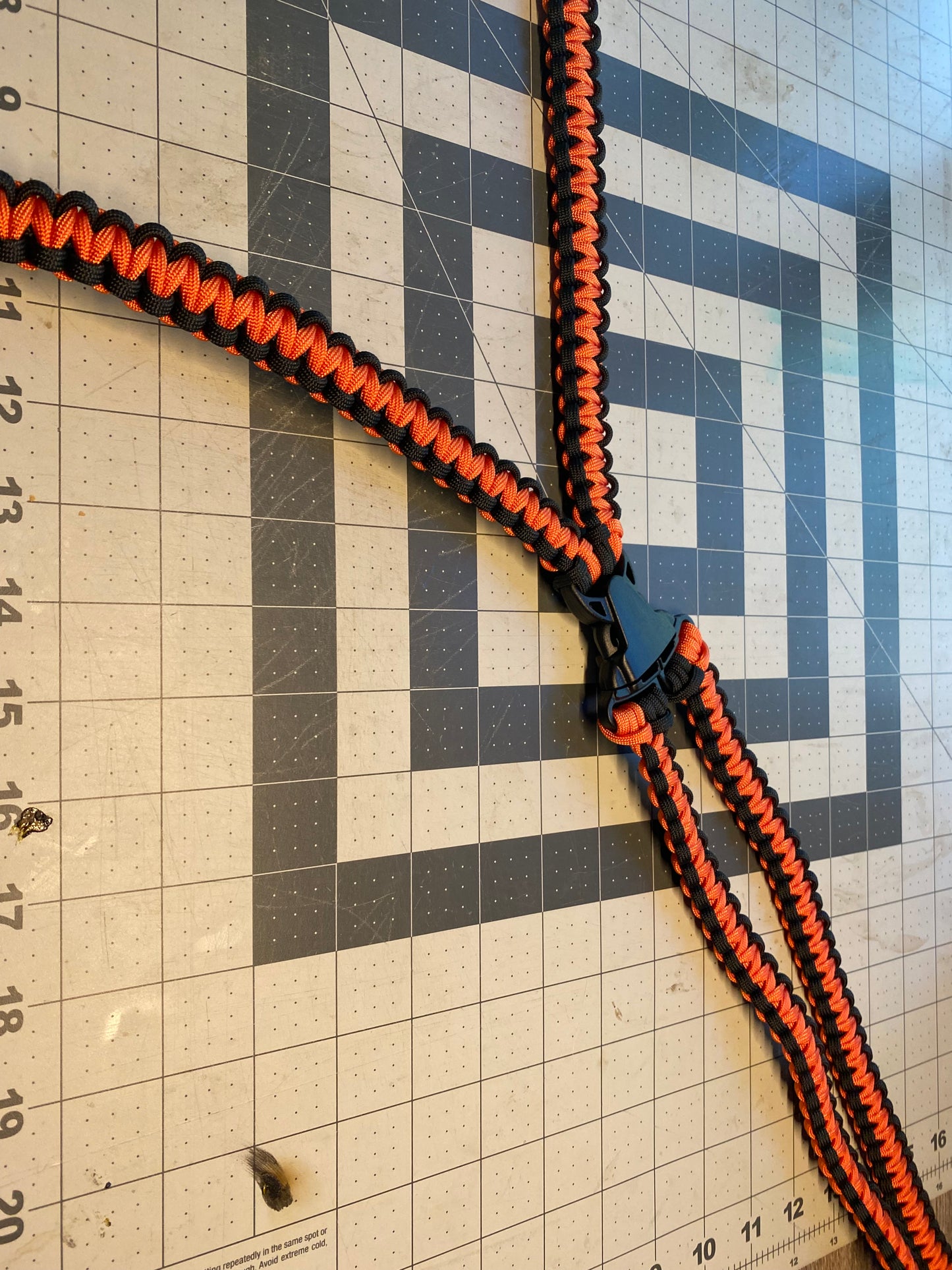a binocular harness crafted from orange and black 550 paracord