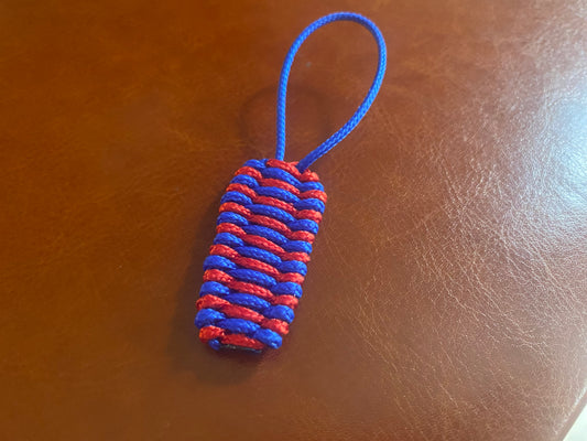 a zipper pull made with red and blue 95 paracord