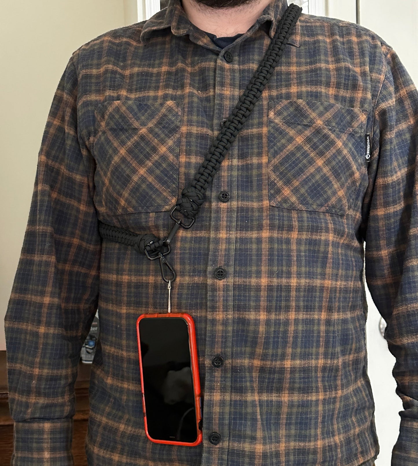 a man wearing a paracord phone lanyard with the phone being carried entirely by the lanyard