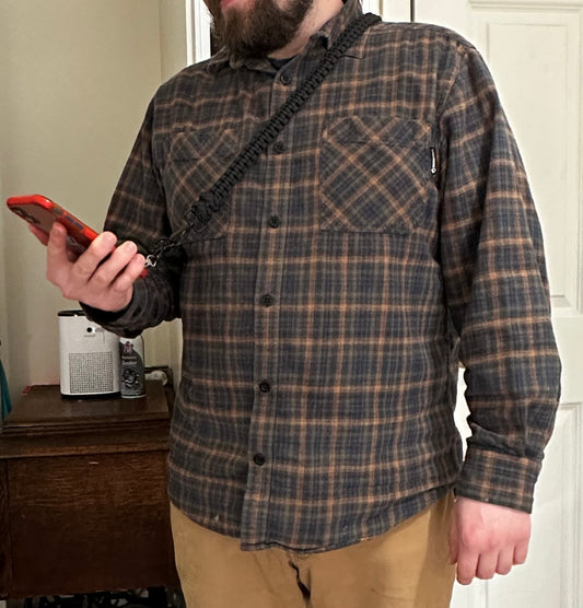 a man viewing his phone while it's attached to a black paracord phone lanyard.