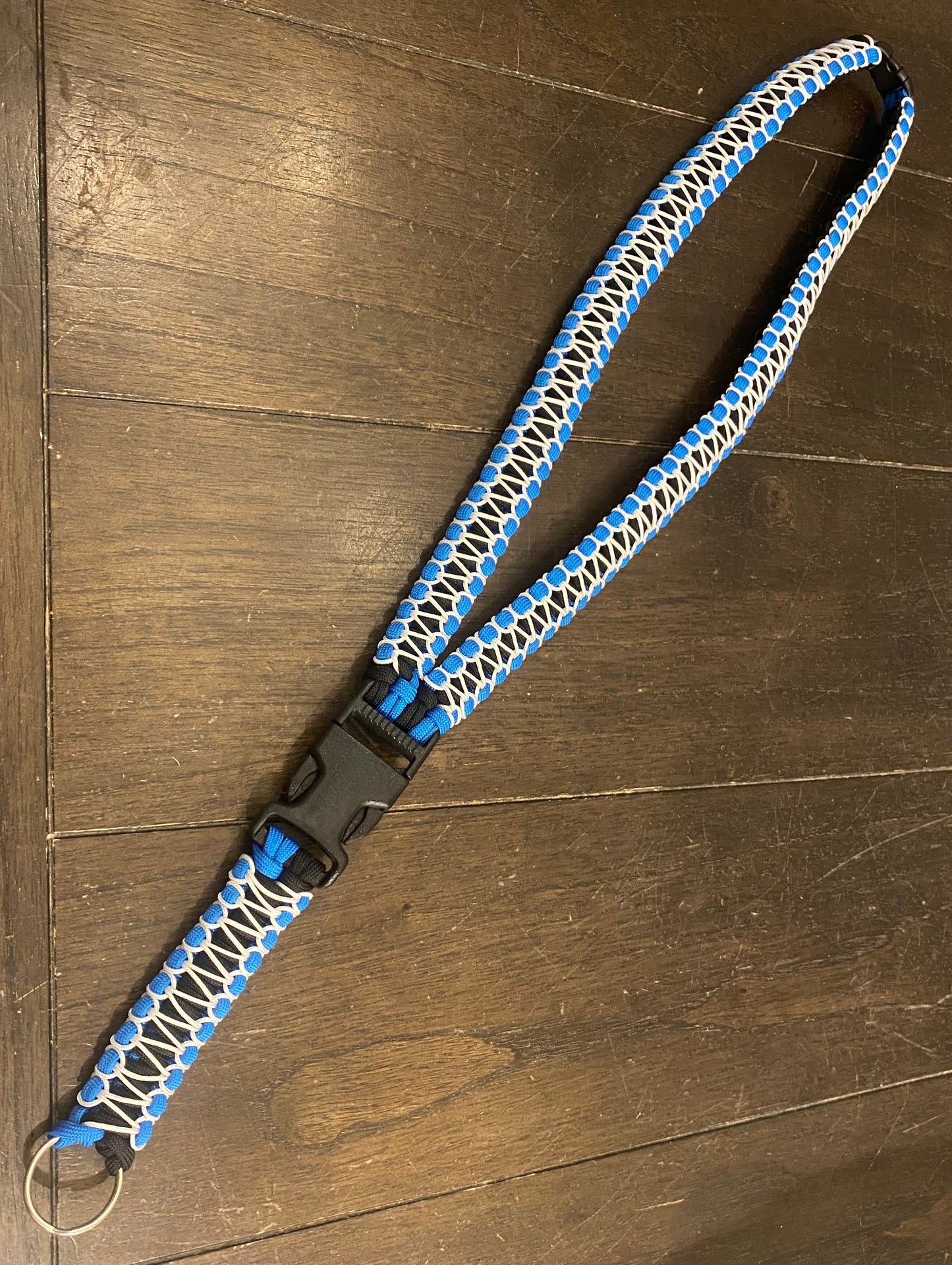 a general lanyard made with blue and black 550 paracord and white microcord stitching