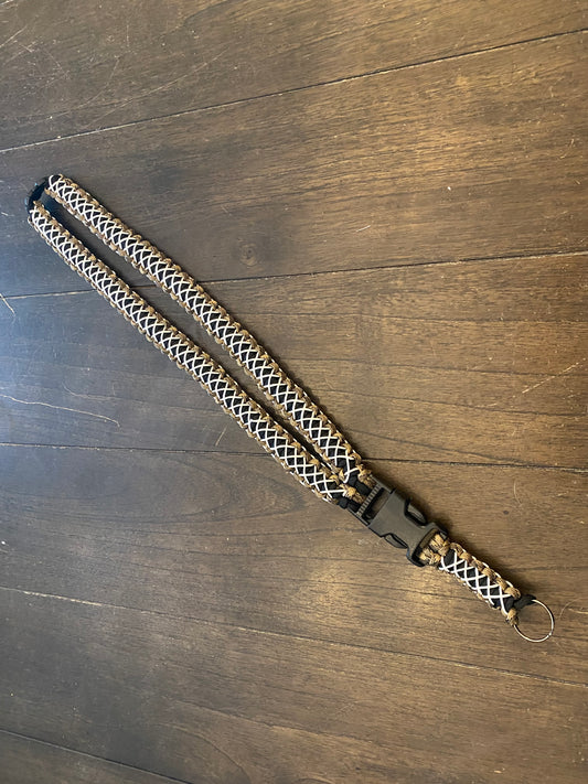 a general lanyard crafted in the cobra weave in FDE camo and black 550 paracord and white microcord