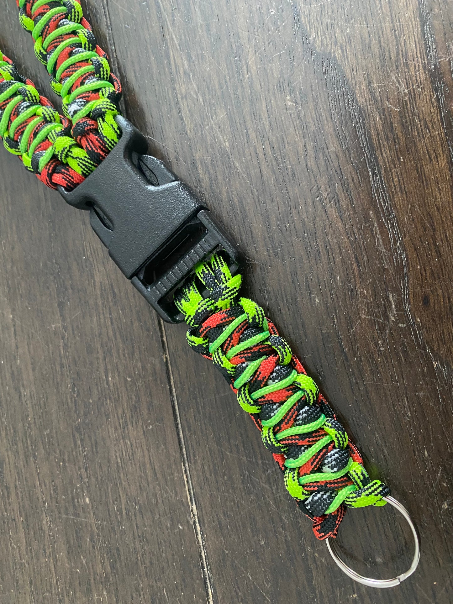 a general ID lanyard made in the soloman's dragon weave in red, black, white 550 paracord and stitched with 275 neon green cord