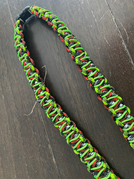 a general ID lanyard made in the soloman's dragon weave in red, black, white 550 paracord and stitched with 275 neon green cord
