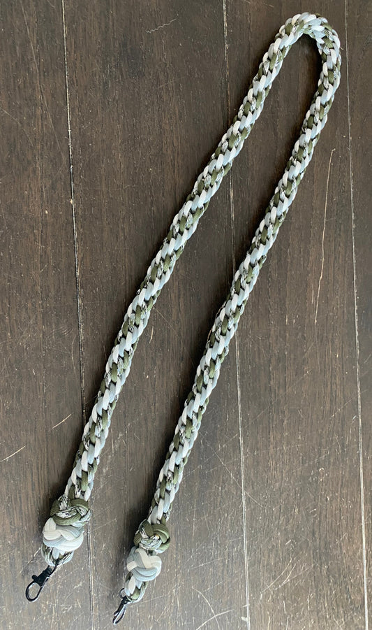 a binocular lanyard made in siberian camo, white, grey, and OD green 550 paracord and finished off with two footrope knots