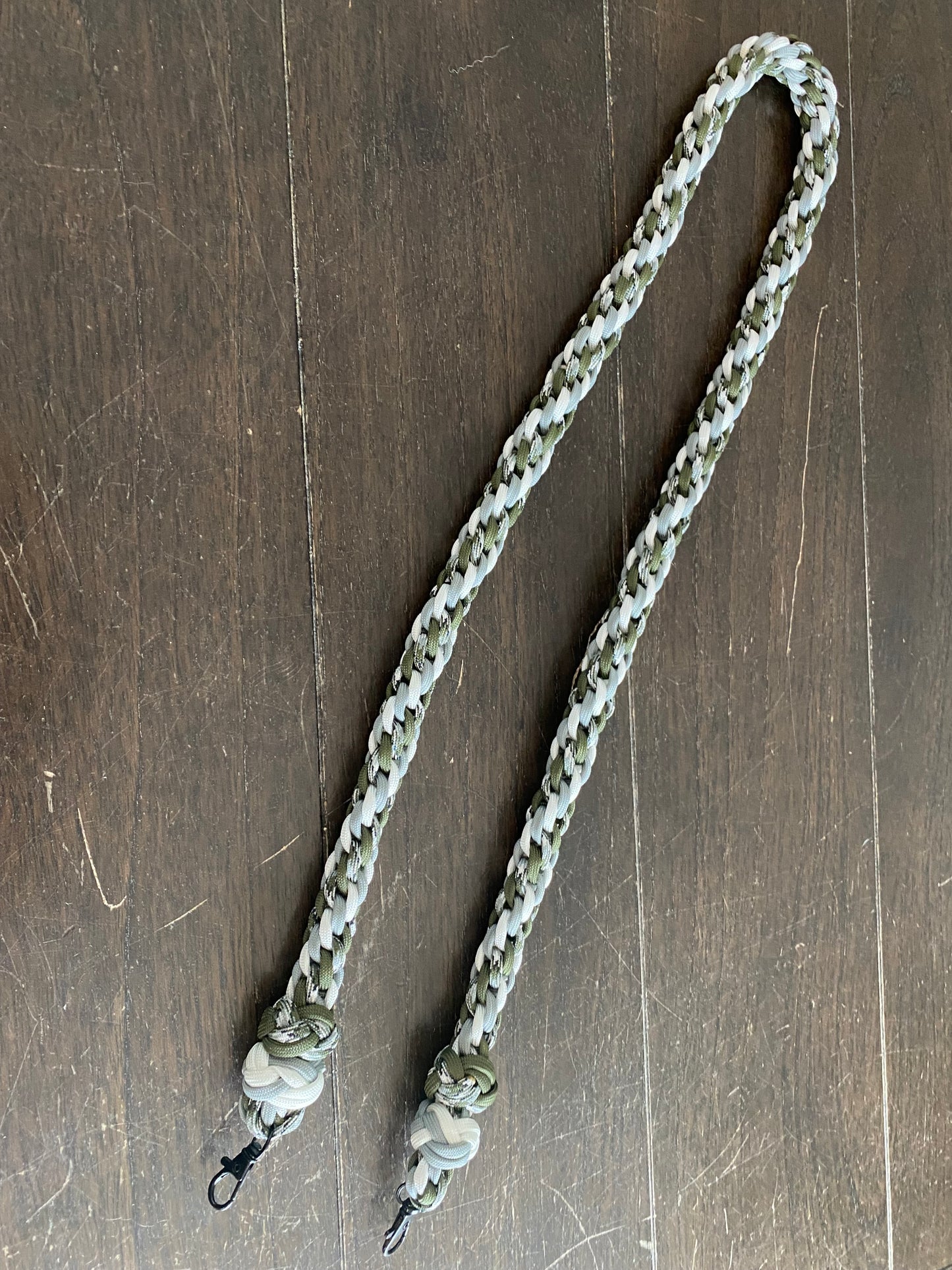 a binocular lanyard made with the Japanese round braid in grey, white, OD green, and siberian camo and finished with two footrope knots