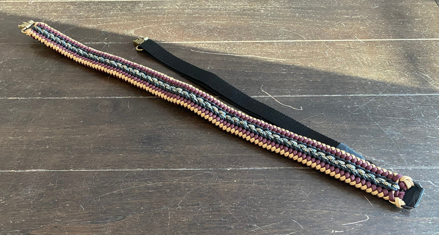 a fancy stitched modified sanctified gun sling made in tan, burgundy, and honor 550 paracord, black 275 cord, and brass trilock swivels