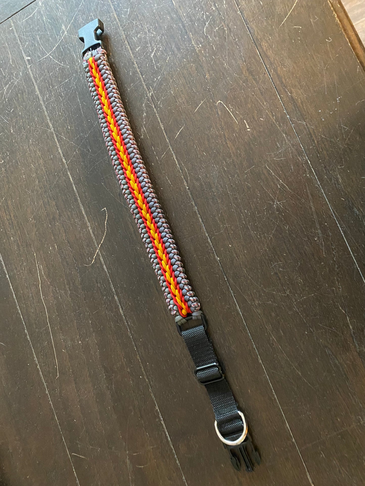 a fancy stitched modified sanctified dog collar made in grey, gold, and patterned grey-and-red-and-white 550 paracord, and red 275 cord.
