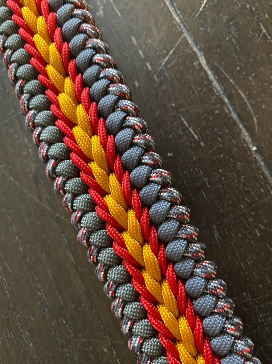 a fancy stitched modified sanctified dog collar made in grey, gold, and patterned grey-and-red-and-white 550 paracord, and red 275 cord.