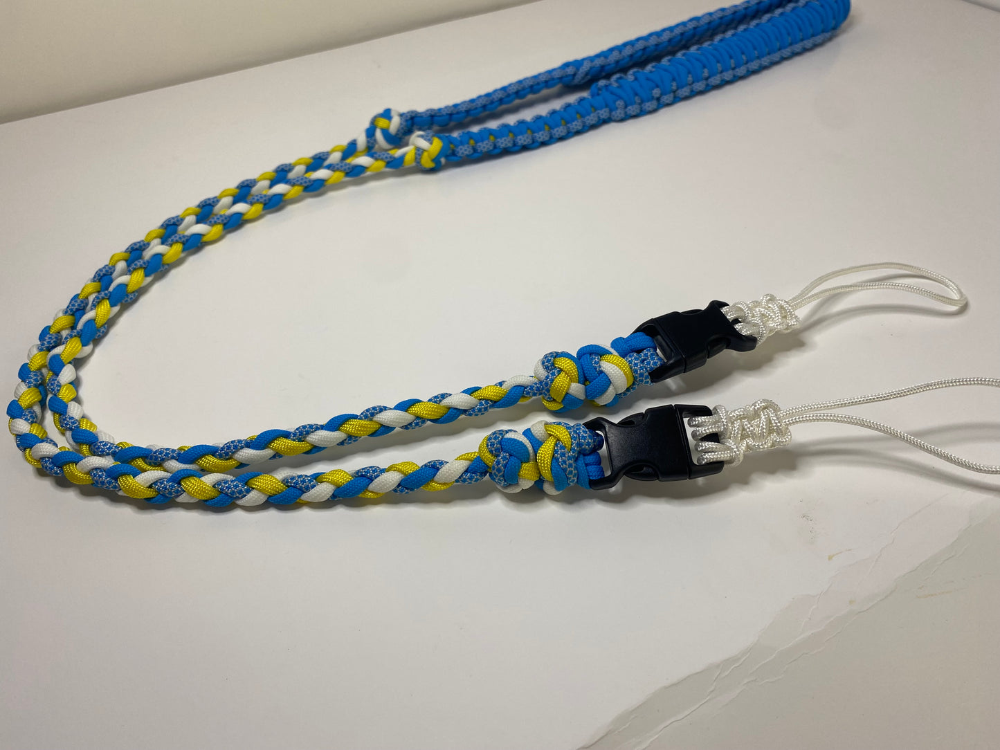a fancy dual-weave paracord binocular lanyard with buckles made in light blue, yellow, and white cord; the neckband is stitched with white microcord.