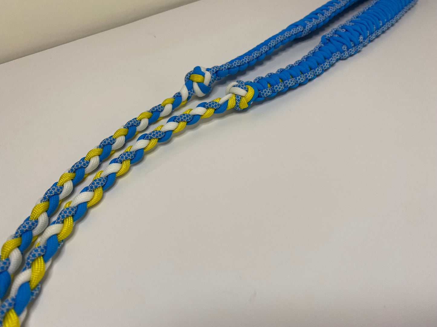 a fancy dual-weave paracord binocular lanyard with buckles made in light blue, yellow, and white cord.