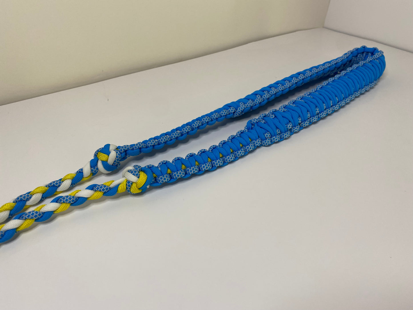 a fancy dual-weave paracord binocular lanyard with buckles made in light blue, yellow, and white cord.