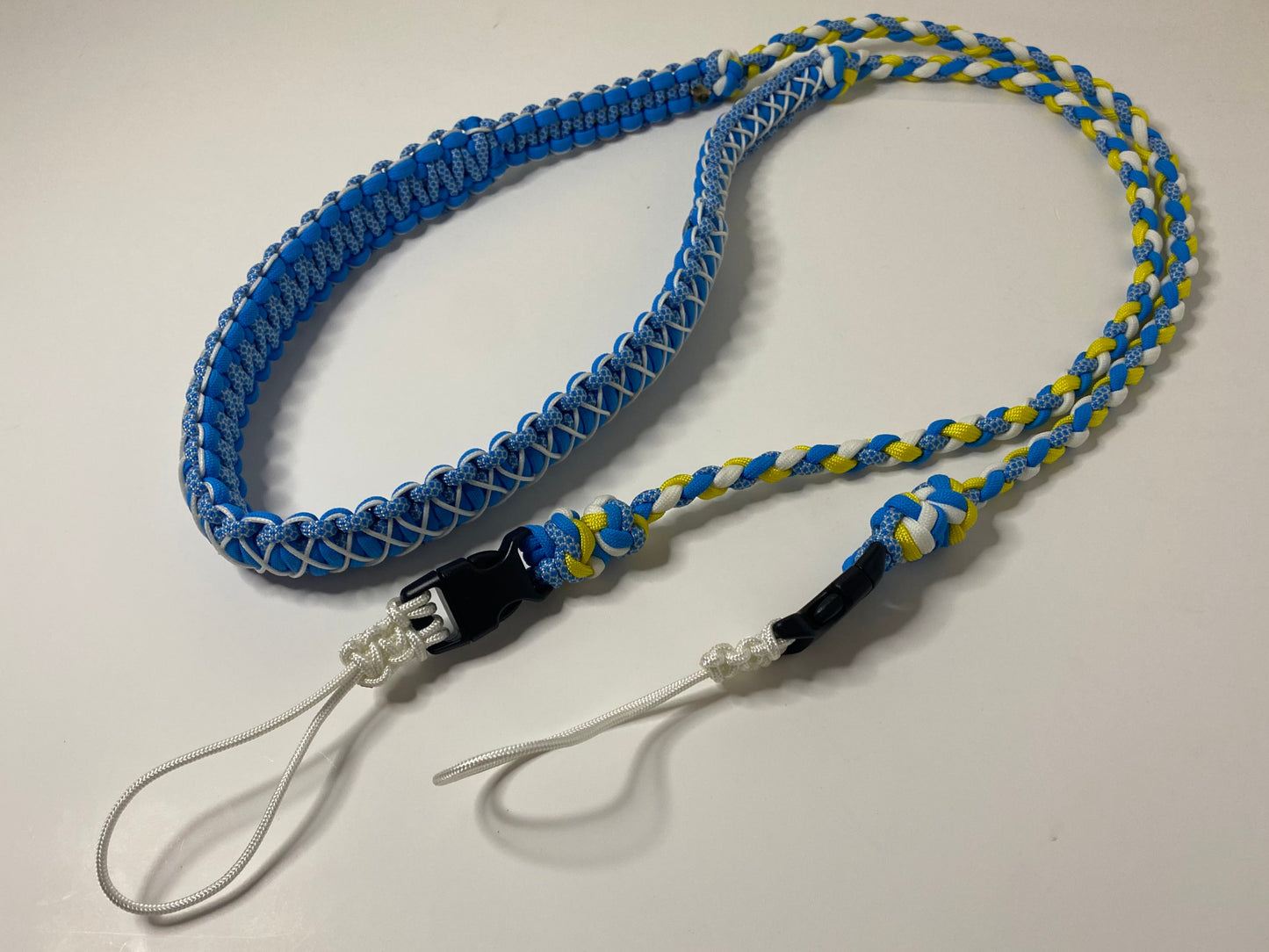 a fancy dual-weave paracord binocular lanyard with buckles made in light blue, yellow, and white cord; the neckband is stitched with white microcord.
