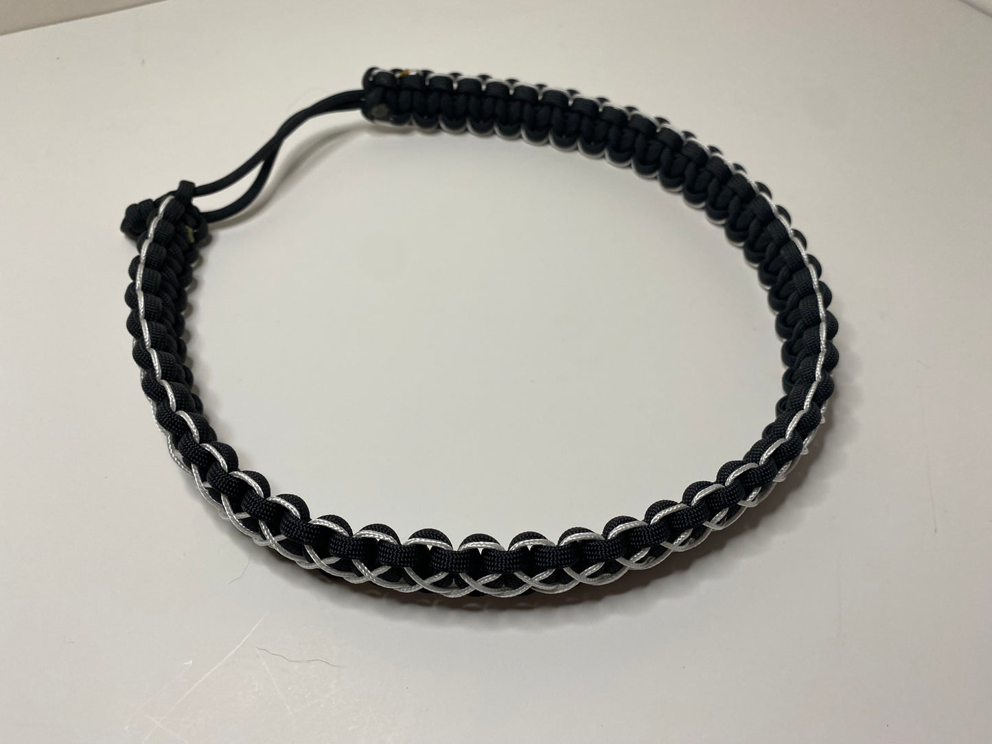 a hat band made in the cobra weave and made in black paracord and stitched with white microcord.