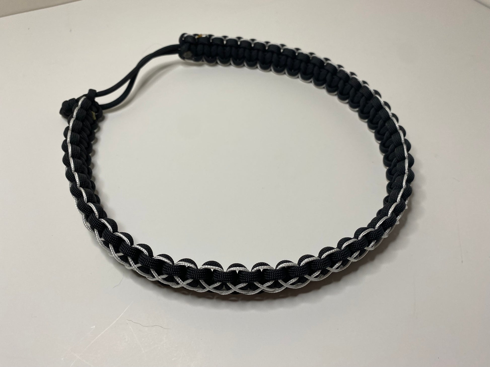 a hat band made in the cobra weave and made in black paracord and stitched with white microcord.