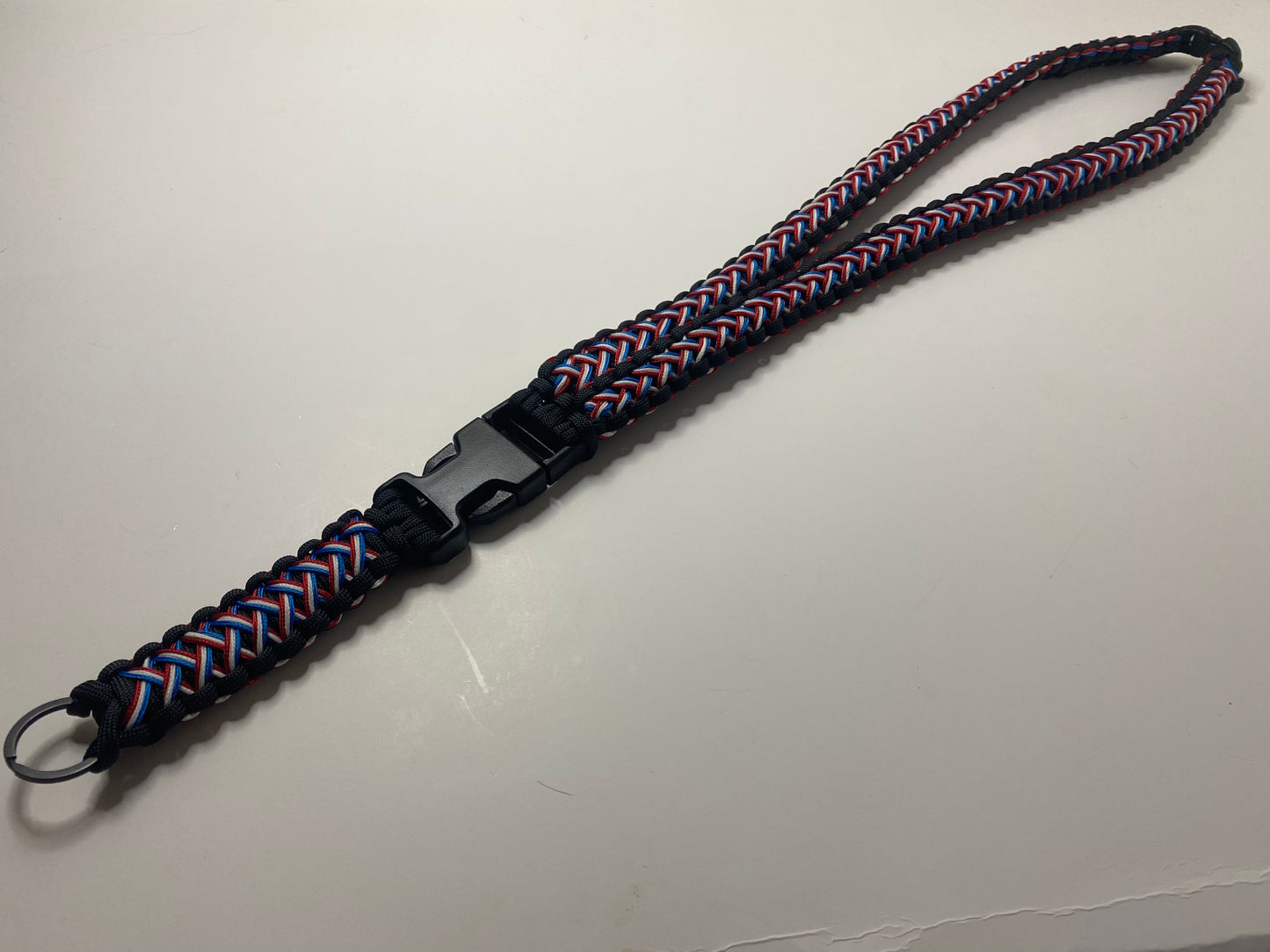 a red, white, and blue patriotic triple stitched paracord lanyard made with black hardware.