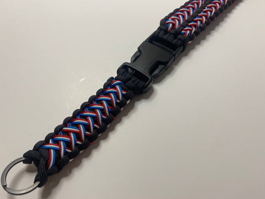a close up of a red, white, and blue patriotic triple stitched paracord lanyard made with black hardware.