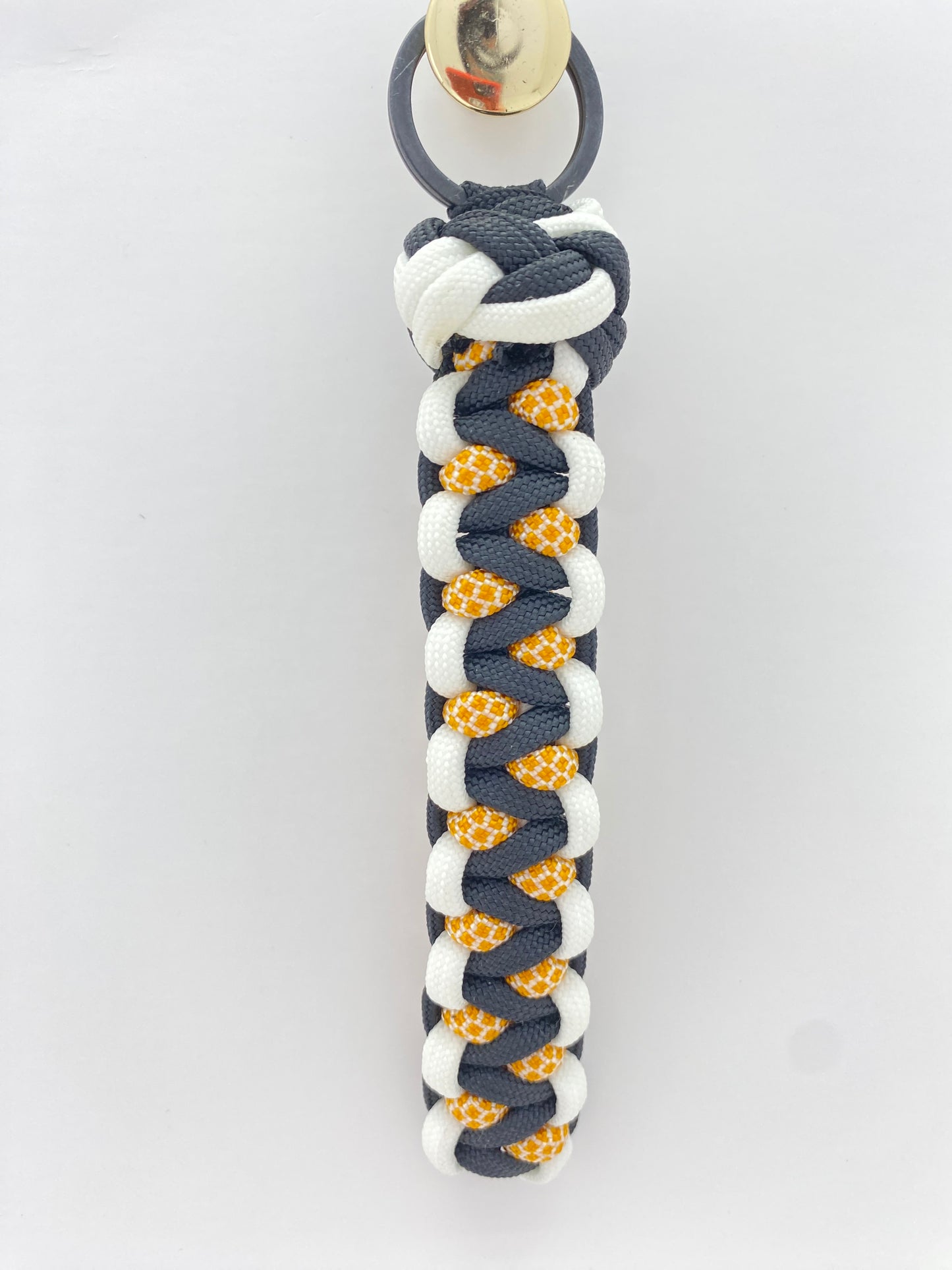 a soloman's dragon woven key chain in black, white, and honeycomb 550 paracord, then finished off with a single footrope knot