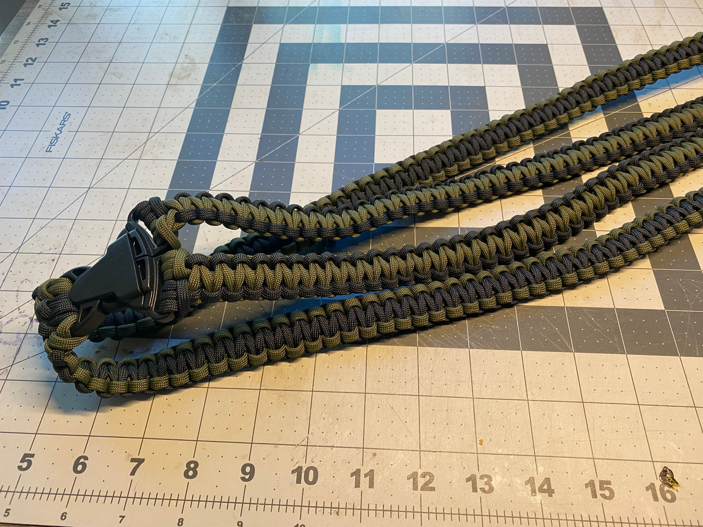 a binocular harness crafted from OD green and black 550 paracord