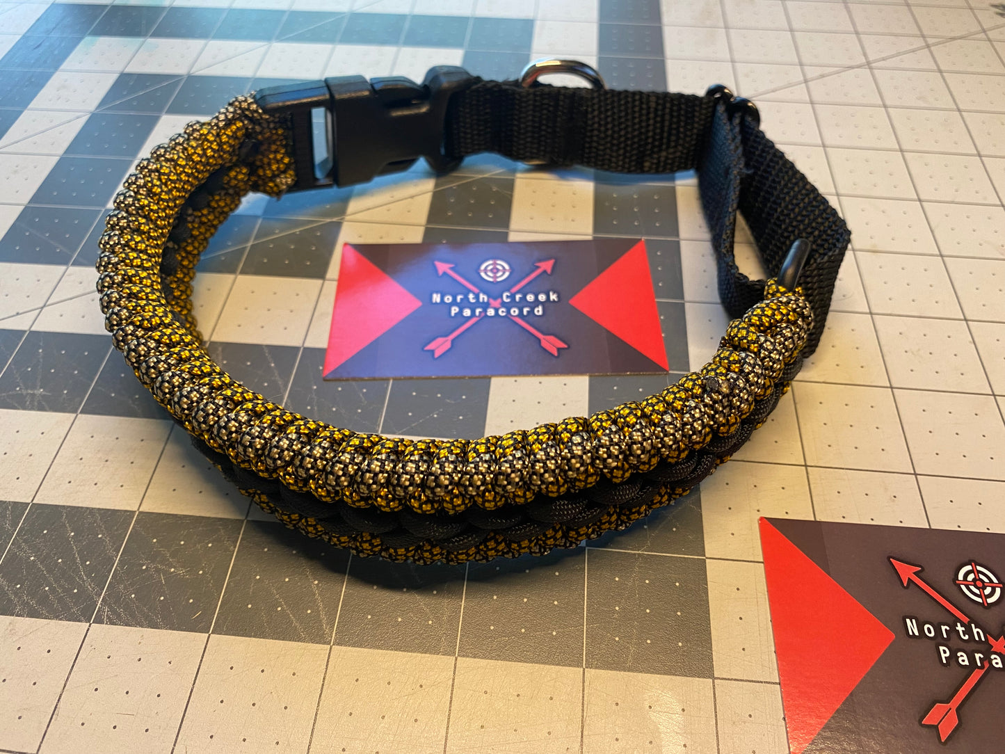 a pet collar built in the modified sanctified weave in gold and tan black diamond paracord and a black center stitching.