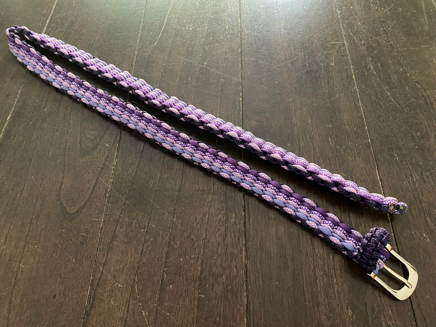 a purple belt crafted with different shades of purple 550 paracord and a silver buckle