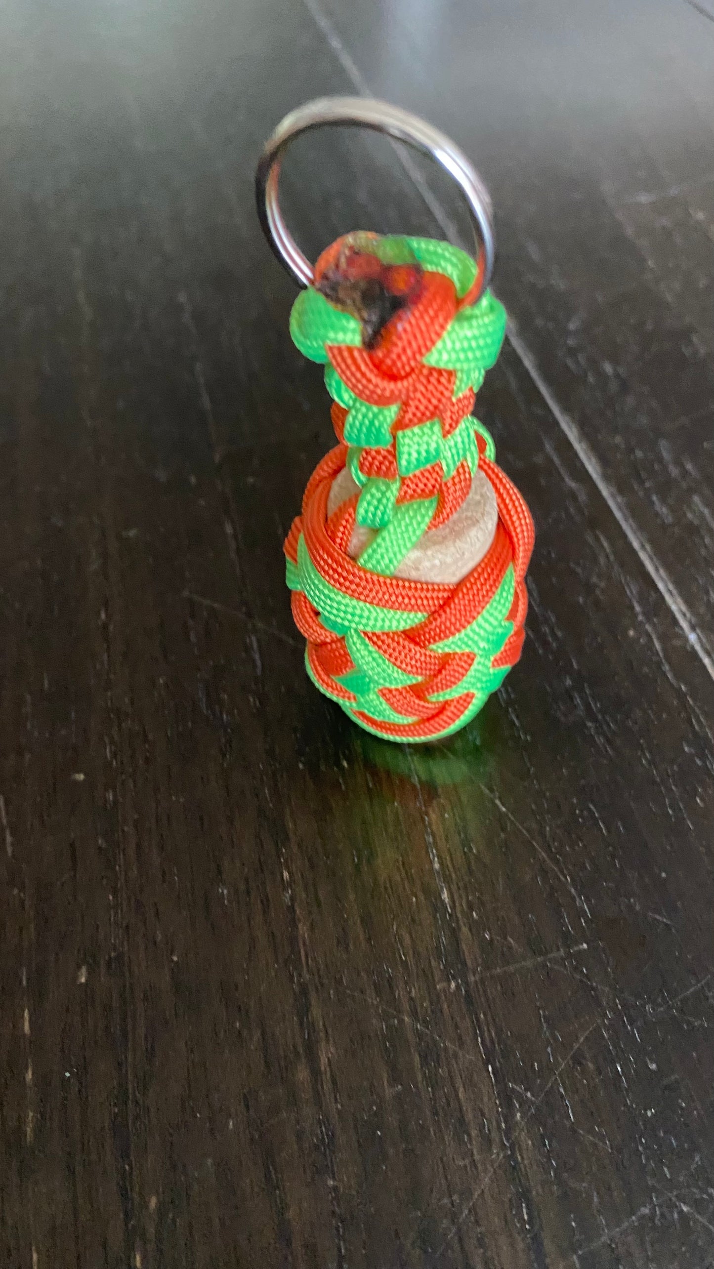 a boat key chain that floats crafted in light green and orange 550 paracord