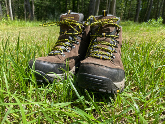 yellow and black 550 paracord bootlaces laced on a pair of boots sitting in the lush green summer grass