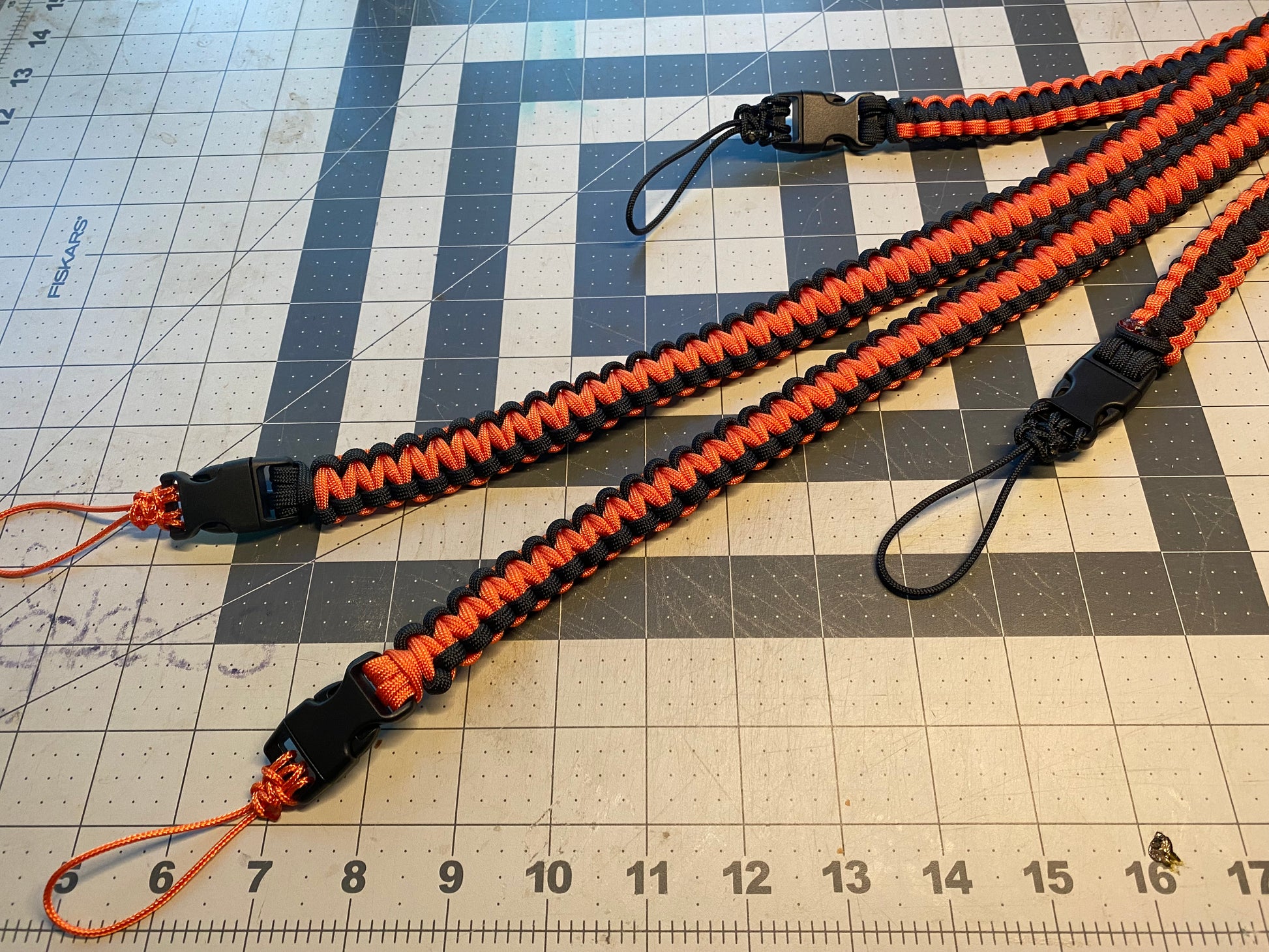 a binocular harness crafted from orange and black 550 paracord