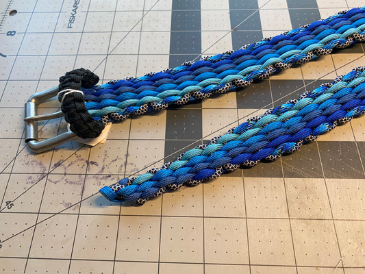 a belt built in shades of blue paracord with a black belt keeper and a silver buckle