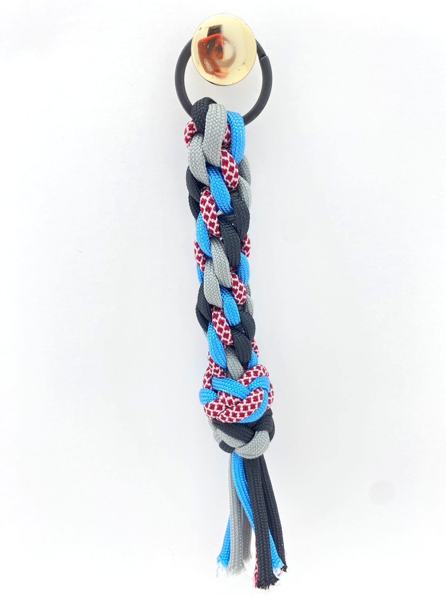 a Japanese round braid woven key chain made in 550 paracord and grey, blue, red, white, and black paracord then finished with two footrope knots