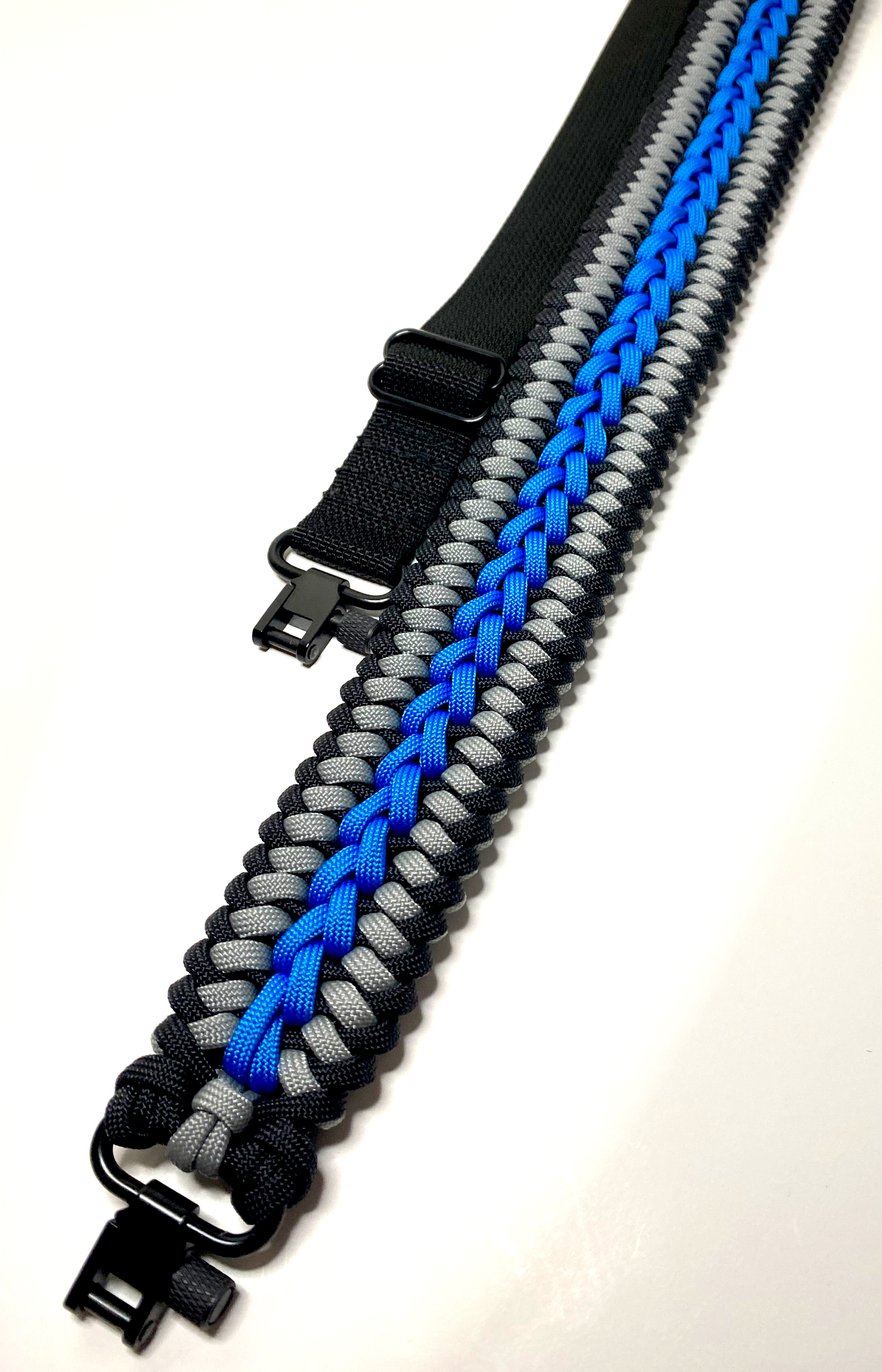 a sanctified modified rifle sling made with black, blue, and gray paracord, black hardware and webbing.