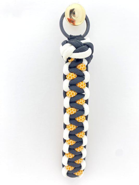 a soloman's dragon woven key chain in black, white, and honeycomb 550 paracord, then finished off with a single footrope knot