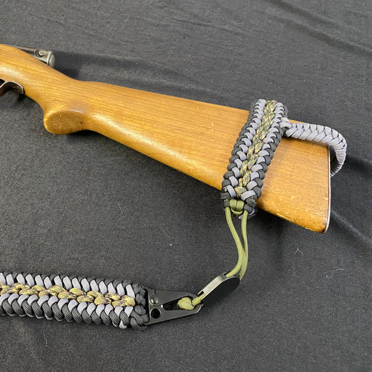 a no drill rifle sling made with paracord attached to the stock of a .22 LR rifle stock.