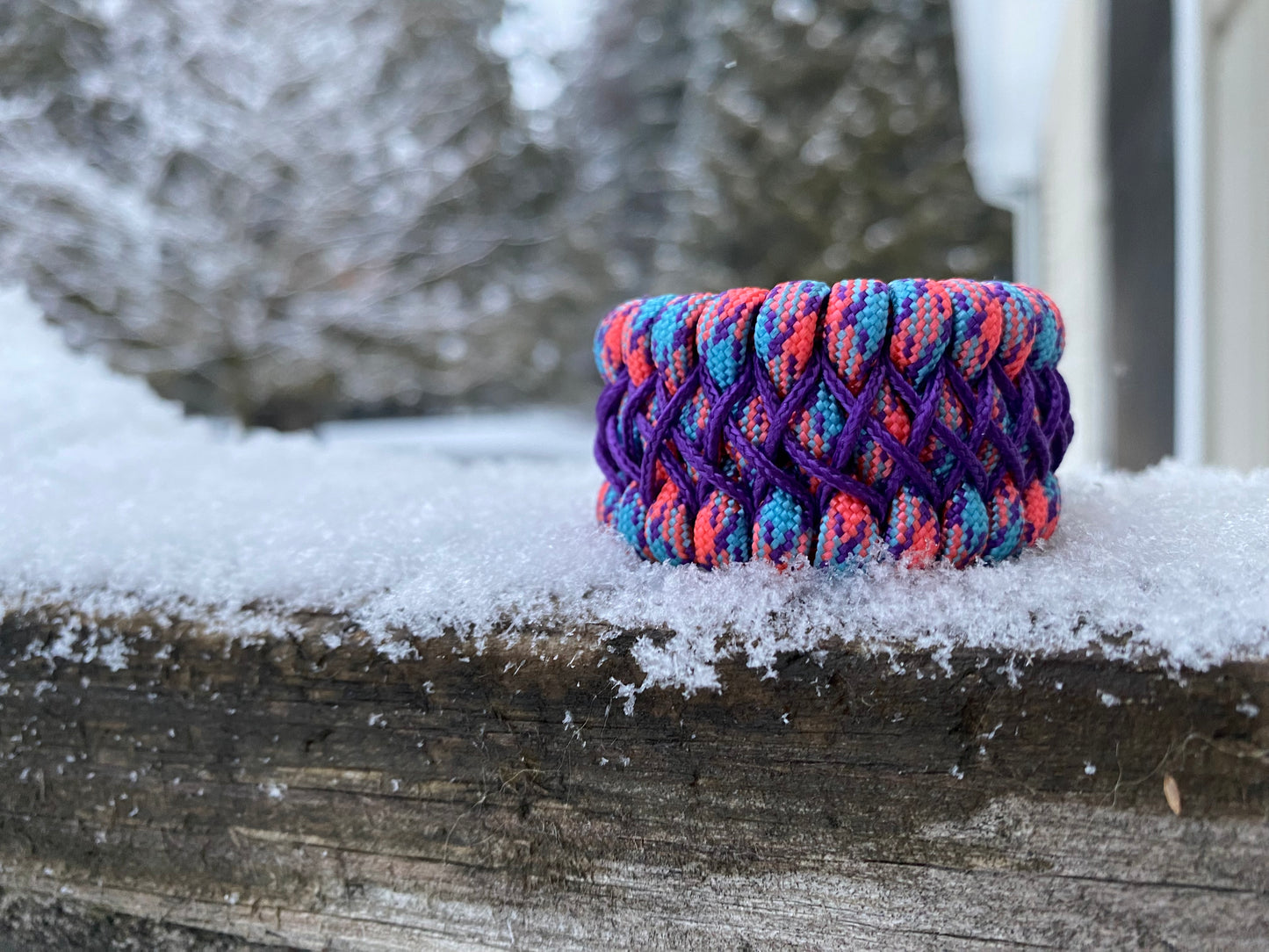 a stitched trilobite bracelet made to be adjustable crafted with purple, pink, and blue paracord and microcord.