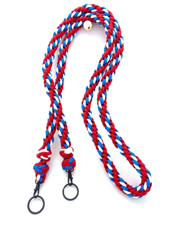 a binocular lanyard made with red, white, and blue paracord and black hardware