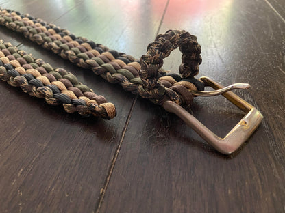 paracord belt made with tan, ollive drab green, black, and camo paracord with similar colors and a sturdy metal buckle.